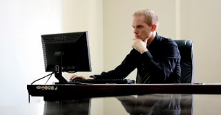 Man looking at a computer with a considering expression
