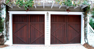 brown garage doors, closed. Trellis with flowers above the doors.