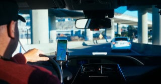 view from behind of a man driving with his phone showing the route