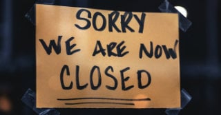 Hand written sign that reads "sorry we are now closed" tapped to a window