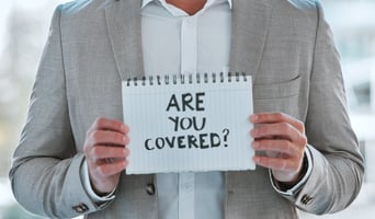 man holding sign that reads "Are you covered?"