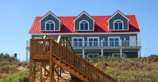 View of a House from the beach with stairs that give the house beach access