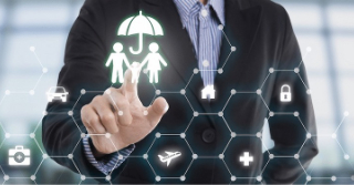 Man in suit touching a graphic of a family under an umbrella.  Graphic is connected to other images in a honeycomb pattern