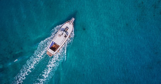 Arial view of a boat on the open water - waters are clear and blue