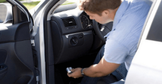 Man plugging in a telematics device into a car on the driver's side