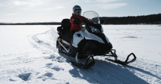 Person riding a snowmobile in a field covered with snow