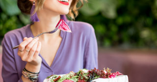 Woman in purple shirt eating a salad