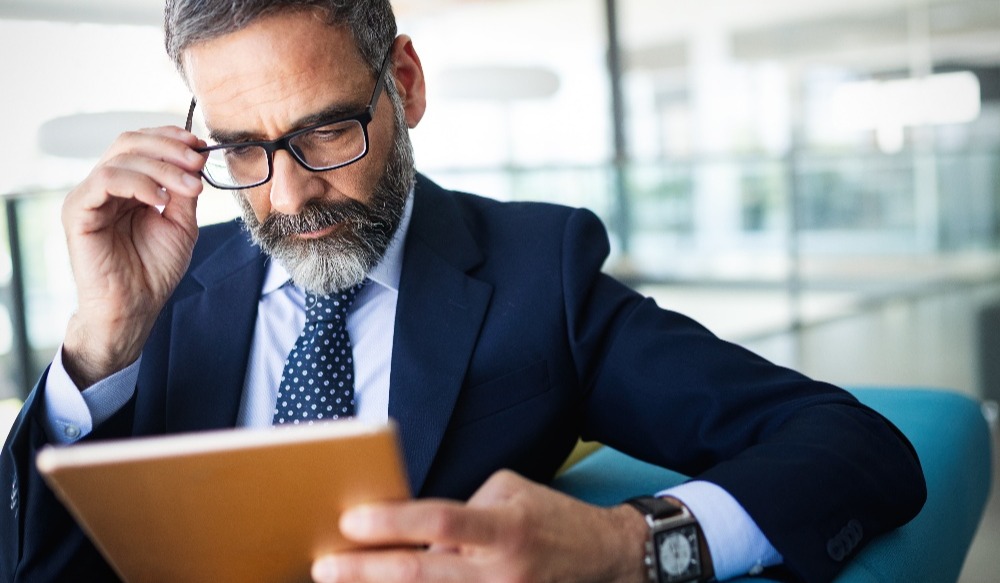 man adjusts glasses while reading report