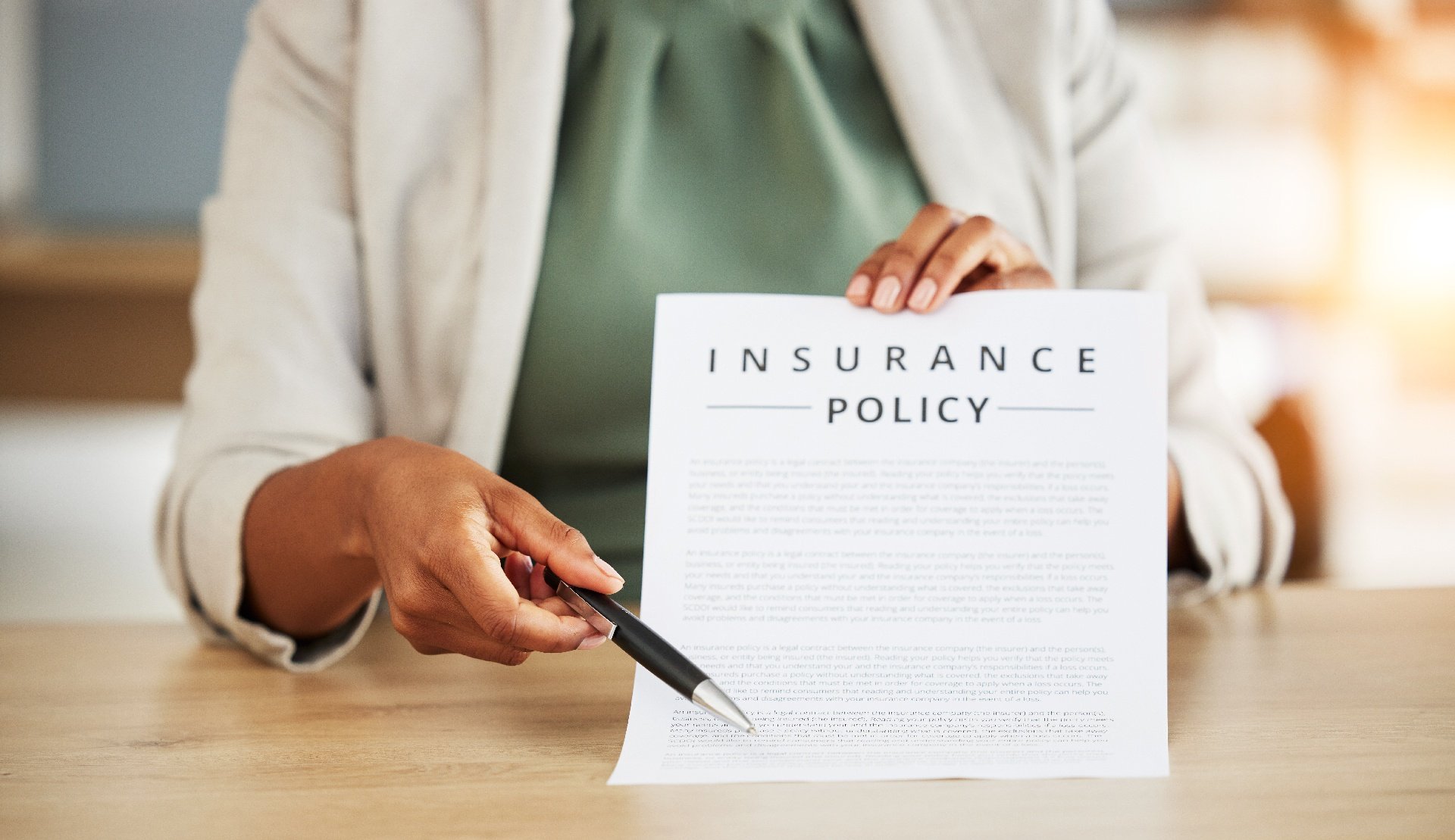Woman holding insurance policy, gesturing to a section with a pen