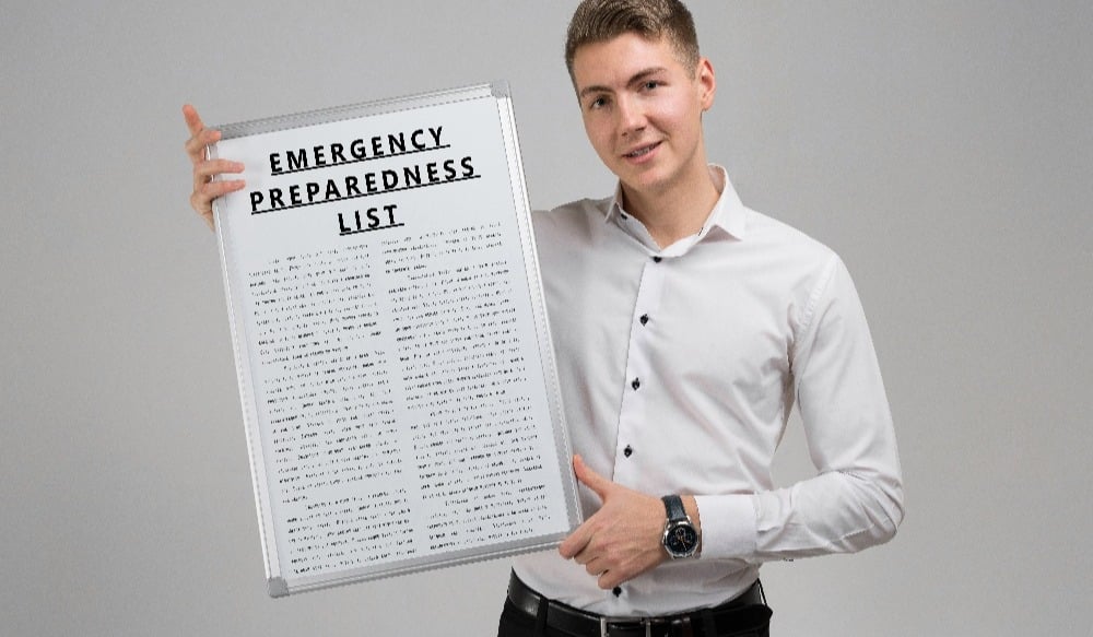 Young man holding a list of Emergency preparedness isolated on a light background